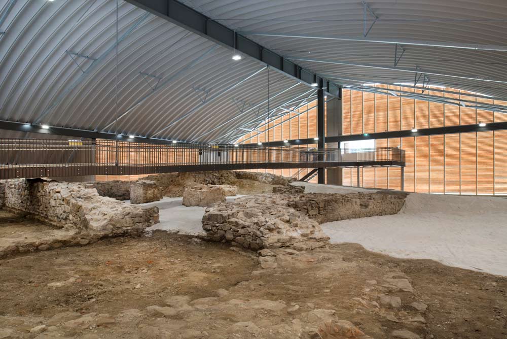 Überdachte archäologische Ausgrabungsstätte in Oberanna mit freigelegten Mauerresten und Stegen für Besucherinnen.